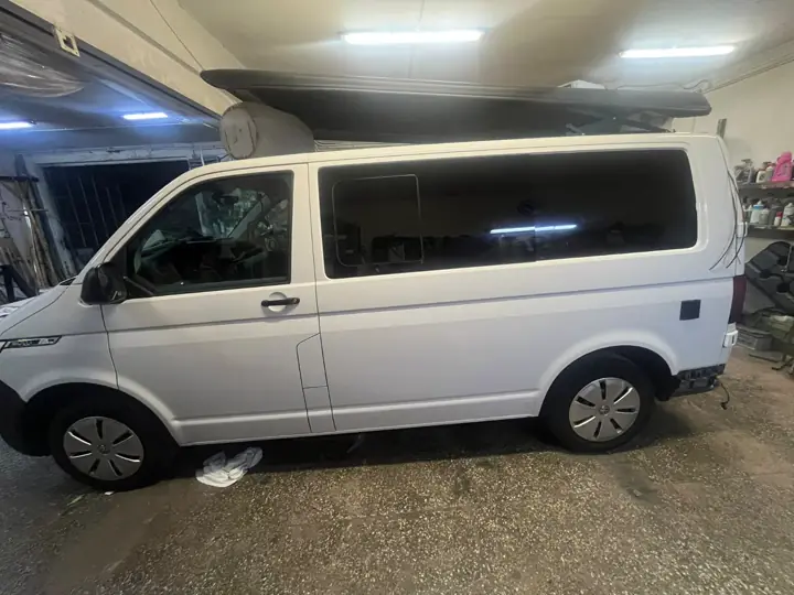 Biały VW T6 z zamontowanym dachem podnoszonym, widok z boku w warsztacie